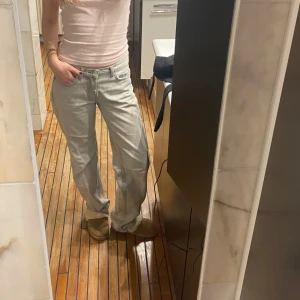 Grå jeansbyxor - Snygga grå jeansbyxor med en klassisk straight passform. Byxorna har en lågmidjad design och är perfekta för en avslappnad stil. De har traditionella fem fickor och en knappgylf.