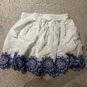 Vit kjol med blå broderi från Abercrombie Kids - Söt vit kjol från Abercrombie Kids med vackert blått broderi längs fållen. Perfekt för en somrig look! 🩵😍😍☺️