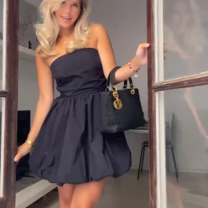 Svart axelbandslös klänning  - Snygg svart axelbandslös klänning med en ballongkjol. Perfekt till festliga tillfällen💕Säljs inte längre och har bara använts en gång💕