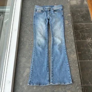 Blå bootcut jeans från Diesel - Snygga blå bootcut jeans från Diesel med klassisk femficksdesign och knappgylf. Jeansen har en lätt tvättad look och är perfekta för en avslappnad stil. Märkeslapp i läder baktill. W27,L30