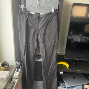 Svarta kostymbyxor från Massimo Dutti - Eleganta svarta kostymbyxor från Massimo Dutti med en klassisk design. Byxorna har en rak passform och är tillverkade i ett bekvämt material. Perfekta för en stilren look.