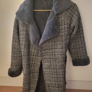 Rutig kappa med teddyfoder - Säljer en snygg rutig kappa med mjukt teddyfoder. Den har en klassisk krage och långa ärmar. Perfekt för kyliga dagar när du vill hålla stilen. Skärp finns🖤