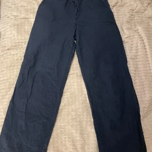 Mörkblå linnebyxor från Gina Tricot - Snygga mörkblå linnebyxor från Gina Tricot med en avslappnad passform. Byxorna har en elastisk midja med snörning för extra komfort. 
