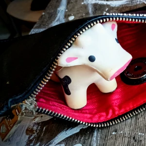 Svart plånbok från Love Moschino - Snygg svart plånbok från Love Moschino med guldfärgad logotyp och dragkedja. Insidan är klädd i rött tyg som ger en lyxig känsla. Perfekt för att hålla ordning på dina kort och kontanter. En stilren accessoar som passar till alla tillfällen.