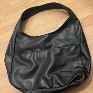 Svart och röd axelväska i syntet - Snygg och rymlig axelväska i både svart och röd färg. Til. Använt flertal gånger men kommer med väldigt bra skick! Får plats med dator och skolböcker! Perfekt för att bära med sig det nödvändigaste.