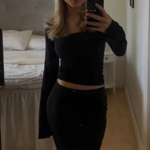 Svart långärmad croppad topp - Säljer en stilren svart långärmad topp med croppad passform. Perfekt för en trendig look.