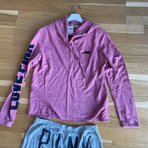 Rosa hoodie och gråa mjukisbyxor från Victoria's Secret PINK - Säljer en rosa hoodie och gråa mjukisar från Victoria's Secret PINK. Tröjan har en bekväm passform och är tillverkad av en bomulls- och polyesterblandning. Perfekt för en avslappnad stil. 💖