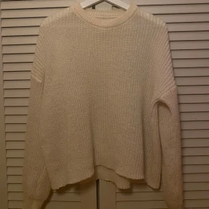 Vit stickad tröja - Mysig vit stickad tröja med rund hals och långa ärmar. Perfekt för kyliga dagar med sin mjuka och bekväma passform. Ribbstickade muddar vid ärmslut och nederkant ger en stilren look.