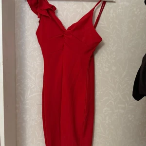 Röd klänning från Shein - Snygg röd klänning från Shein med volangdetalj på axeln och smala axelband. Perfekt för en kväll ute eller en speciell tillställning. Klänningen har en figurnära passform och en dragkedja i ryggen.