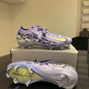 Fotbollsskor - Snygga lila Nike fotbollsskor med limegröna detaljer och snörning. Skorna har en modern design med mönster och är utrustade med Air Zoom-teknologi för optimal prestanda på planen.