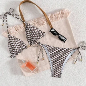 Brun och vit bikini med knyt - Trendig bikini i brunt och vitt med ett unikt mönster. Överdelen har knytband runt nacken och ryggen, medan underdelen har knyt i sidorna för justerbar passform. Perfekt för en dag på stranden eller vid poolen.