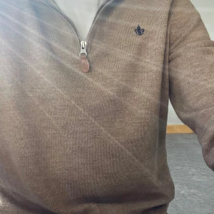 Brun/beige halfzip från Morris - Säljer en stilren brun tröja med dragkedja och en liten broderad detalj på bröstet. Perfekt för en avslappnad look. Tröjan har långa ärmar och en bekväm passform.100% merinoull,nypris runt 1500.För fler bilder kontakta mig