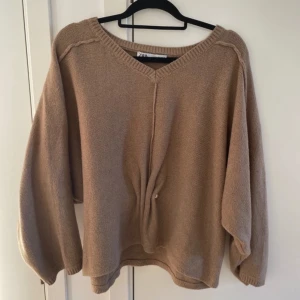 Beige stickad tröja från Zara - Säljer en mysig beige stickad tröja från Zara. Tröjan har en v-ringad design och långa ärmar. Perfekt för kyligare dagar. Den har en enkel och stilren look som passar till det mesta. Hör av dig vid intresse! 😊
