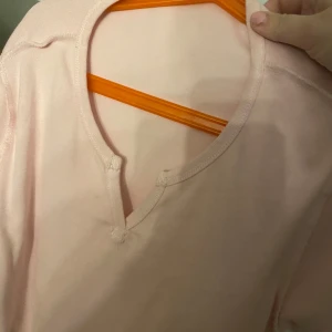 Ljusrosa tröja med v-ringning - Säljer en ljusrosa tröja med v-ringning. Perfekt för en avslappnad stil. Tröjan har en enkel design och är gjord i ett mjukt material.