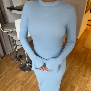 Ljusblå ribbad klänning med öppen rygg från NA-KD - Säljer min sambos klänning från NA-KD. Storlek 38, en trasig knapp i nacken (se bild) som inte påverkar användningen då det finns två knappar, i övrigt är den i fint skick.