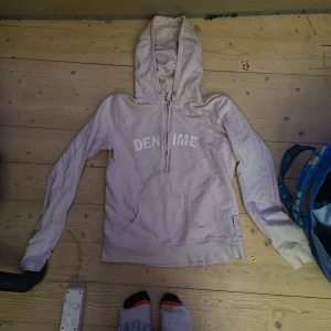 Ljusrosa hoodie från Gina Tricot - Säljer en ljusrosa hoodie från Gina Tricot med texten 'DENIME' på framsidan och en vit tryckdetalj på baksidan. Tröjan har en dragkedja vid halsen och en stor ficka framtill. Perfekt för en avslappnad stil.