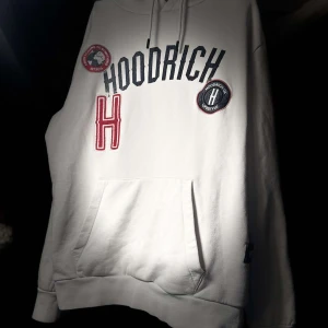 Vit hoodie från Hoodrich - Säljer en stilren vit hoodie från Hoodrich med tryck och broderade detaljer i svart och rött. Hoodien har en klassisk känguruficka och justerbar huva med snören. Perfekt för en avslappnad stil. Storlek M men passar S också, pris kan diskuteras 