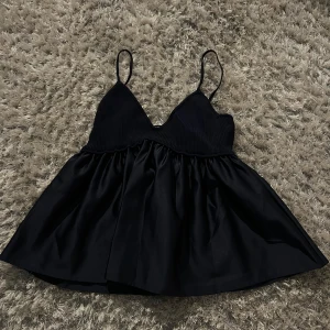 Fest topp från Zara - Snygg mörkblått linne från Zara med smala axelband och v-ringad design. Toppen har en ribbad överdel och en luftig nederdel som ger en fin siluett. Perfekt för varma dagar eller som ett lager under en jacka.