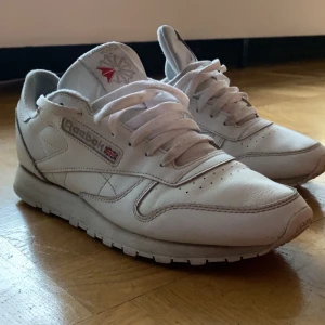 Vita sneakers från Reebok - Säljer ett par klassiska vita Reebok sneakers med snörning och låg profil. Skorna har en stilren design med Reebok-loggan på sidan och tungan. Perfekta för en avslappnad stil. Passar även 42 
