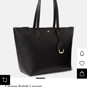 Svart axelväska från Lauren Ralph Lauren - Elegant svart axelväska från Lauren Ralph Lauren. Väskan har en stilren design med en liten logotypdetalj i guld och en praktisk dragkedja. Perfekt för att bära dina dagliga nödvändigheter med stil. Utsprungspris 1595kr