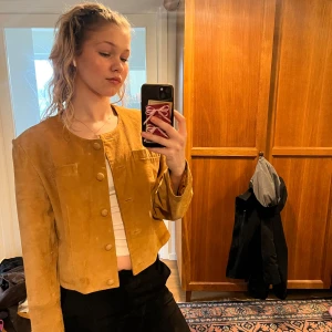 Beige mockajacka med knappar - Säljer en snygg beige mockajacka med rund hals och knappar framtill. Jackan är croppad och har en stilren design som passar perfekt för höst och vår. Den har långa ärmar och en mjuk känsla. Har inte använt jackan mycket och den är väl omhändertagen🥰priset kan diskuteras💕