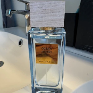 Ocean Infini parfym från Rituals - Säljer en elegant parfymflaska från Rituals med doften Ocean Infini. Flaskan är i glas med en stilren, fyrkantig design och har en träliknande kork. Perfekt för den som älskar fräscha och marina dofter.