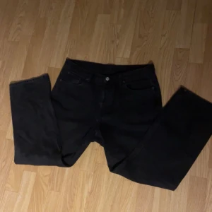 Svarta jeans från Weekday - Snygga svarta jeans från Weekday i en klassisk straight fit. De har en midwaist och är tillverkade i ett slitstarkt material. Perfekta för en stilren look. Hör av dig för övriga frågor