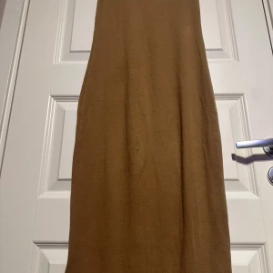 Beige ärmlös klänning - Snygg beige långklänning i ribbat material. Klänningen är ärmlös med en rund halsringning, perfekt för en stilren look.