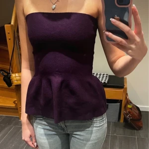 Mörklila tubtopp - Snygg mörklila tubtopp med peplumdetalj som ger en fin siluett. Perfekt för en stilren look. Passar bra till både jeans och kjol.