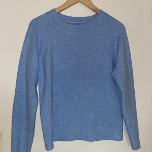 Blå stickad tröja från Vero Moda - Säljer en snygg blå stickad tröja från Vero Moda. Tröjan har en enkel design med långa ärmar och rund halsringning. Perfekt för kyligare dagar. Passar bra till jeans eller kjol för en avslappnad look.