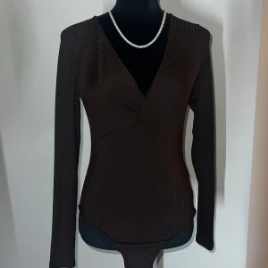 Brun ribbad omlottopp - Snygg brun ribbad omlottopp med långärmad design och v-ringning. Perfekt för en stilren look.