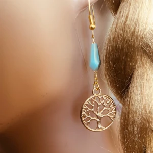 Made by prisförslag- 1 st Örhänge med livets träd och turkos detalj - Elegant örhängen med ett hänge i form av livets träd i guldton. Ovanför trädet finns en turkos detalj som ger en fin kontrast. Perfekt för att ge en naturlig touch till din stil.