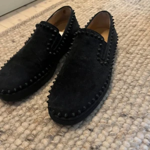 Christian. Louboutins loafers - Snygga svarta loafers i mocka med dekorativa nitar runtom. Perfekta för en stilren look. De har en bekväm passform och är lätta att ta på. Den är av märket Christian Louboutin har kvitto men inget annat