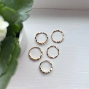 Set med guldiga ringar - Säljer ett set med fem guldiga ringar i olika design. Två av ringarna har en unik blixt-form och de andra tre har en tvinnad design med små stenar. Perfekt för att mixa och matcha för olika stilar. Jag lägger ringarna i plastfickan som finns på sista bilden, så de inte utsätts för skada under leverans.