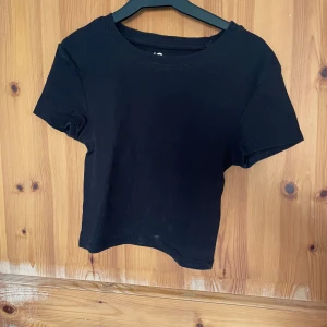 Svart ribbad topp från FSBN Sister - Säljer en svart ribbad topp från FSBN Sister i storlek XS. Toppen har korta ärmar och en enkel design som passar perfekt till vardags. Tillverkad i ett mjukt och bekvämt material.