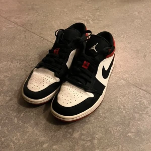 Nike Air Jordans  - Snygga Nike Air Jordans i en klassisk färgkombination av svart, vitt och rött. Skorna har en ikonisk design med snörning och den välkända Jumpman-loggan på plösen. Perfekta för dig som vill ha en stilren och sportig look.