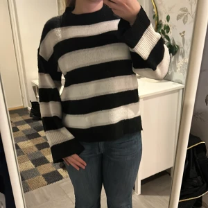 Randig svart och vit tröja - Säljer en mysig randig tröja i svart och vitt. Tröjan har långa ärmar och en avslappnad passform, perfekt för kyligare dagar. Den är tillverkad i ett mjukt material som känns skönt mot huden. Passar bra till jeans eller kjol för en avslappnad look.
