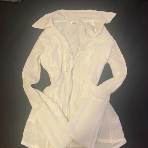 Vit blus från La Muse - Elegant vit blus från La Muse med långa ärmar och knappar framtill. Blusen har en krage och är tillverkad i ett lätt och luftigt material som ger en stilren look. Perfekt för att lyfta vilken outfit som helst.