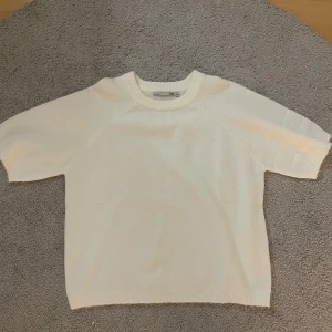 Vit stickad tröja från COS - Säljer en stilren vit stickad tröja från COS. Tröjan har korta ärmar och en klassisk rund halsringning. Perfekt för en minimalistisk look. Passar bra till både jeans och kjol.
