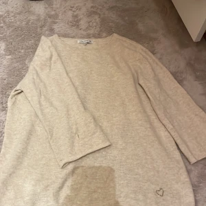 Beige tröja från Flashwoman - Säljer en beige tröja från Flashwoman i storlek M. Tröjan har trekvartsärmar och en unik omlottdesign på baksidan. 