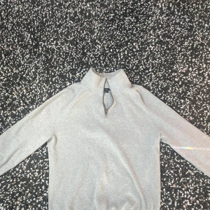 Grå tröja med dragkedja från Massimo Dutti - Säljer en stilren grå tröja från Massimo Dutti, tillverkad i fin bomull. Tröjan har en praktisk dragkedja vid halsen och långa ärmar. Perfekt för en elegant och avslappnad look.