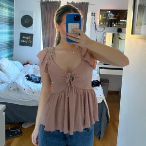 Rosa blus med volangdetaljer - Säljer en söt rosa blus med volangdetaljer och knytning framtill. Perfekt till sommaren. Säljer då den ba ligger i garderoben. Använd 1 gång. Storlek S. 60kr+frakt💖