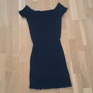 Svart klänning från Gina Tricot - Snygg svart klänning från Gina Tricot med en tight passform. Klänningen är off shoulder och har en ribbad struktur. Endast använd 1 gång✨️