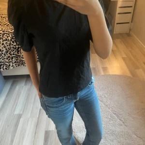 Svart topp med puffärmar - Säljer en stilren svart topp med puffärmar. Toppen har en normal passform och är perfekt för både vardag och fest. Den är tillverkad i ett mjukt material som ger en bekväm känsla hela dagen.