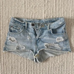 Lågmidjade jeansshorts - Säljer dessa supersnygga jeansshorts med låg midja och hål💗 Perfekta till sommaren!! Passar xs-s. Midjemått 37 cm