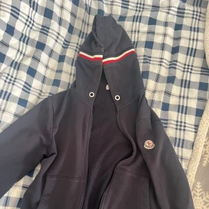 Moncler zip Hoodie  - Säljer nu en klassisk Moncler zip Hoodie. Riktigt snygg passform för dom med storlek S-M. Nypris ca 8000 mitt pris 699 pga använda ganska mycket men fortfarande i bra skick och drag kedjan är trasig men går att fixa lätt för typ 200 kr!