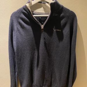 Mörkblå tröja med dragkedja från Bondelid  - Säljer en stilren mörkblå tröja från Brooked med dragkedja och ribbade detaljer. Perfekt för kyligare dagar med sin långärmade design och bekväma passform.