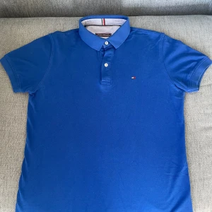 Blå pikétröja, Tommy Hilfiger  - Snygg blå pikétröja från Tommy Hilfiger i storleken M men sitter lite smalare, Den är vi väldigt bra skick, där jag knappt har andvänt den. Hör av er vid intresse, pris kan diskuteras!