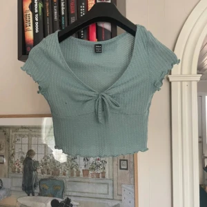 Grön ribbad topp från SHEIN - Säljer en söt grön ribbad topp från SHEIN. Toppen är croppad med korta ärmar och har en knytning framtill. Perfekt för en avslappnad stil.