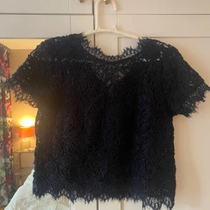 Svart spetsblus från Holly & Whyte - Säljer en elegant mörkblå spetsblus från Holly & Whyte. Blusen har korta ärmar och ett vackert spetsmönster som ger en sofistikerad look. Perfekt för att lyfta vilken outfit som helst. 🖤Kontakta mig privat om ni vill ha en bild på!